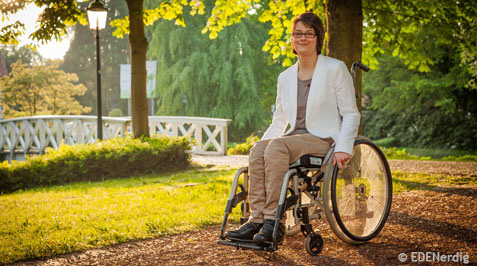 Junge Frau im Rollstuhl unterwegs im Park
