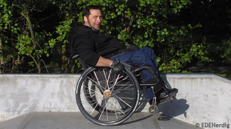 Mann im Rollstuhl steht grinsend nur auf zwei Raedern